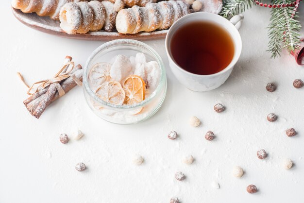 Tè di natale con pasticcini, un ramo di abete verde, biscotti sparsi, un biscotto di lumaca con crema proteica