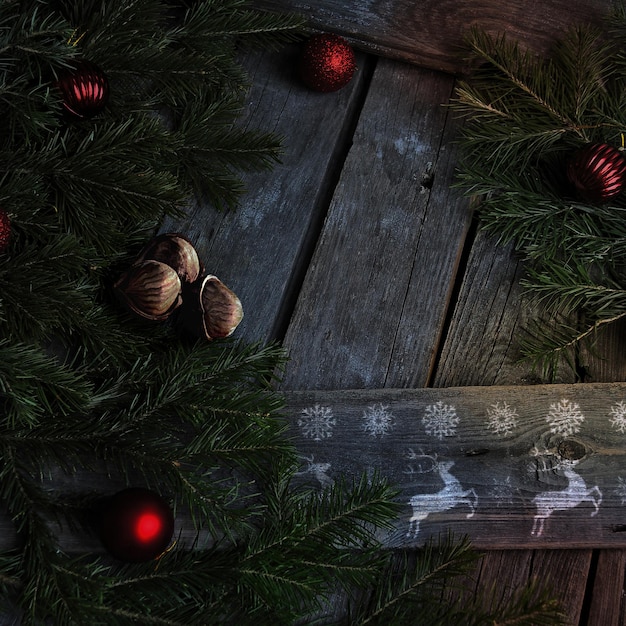 christmas template on dark wooden boards with spruce branch and decorations.