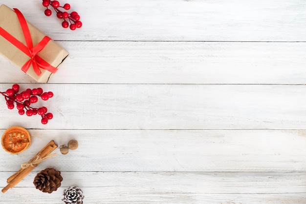 クリスマスのテーマクリスマスギフトボックス、ヒイラギの果実と白い木の板の装飾と背景。クリエイティブフラットレイアウトとトップビュー構成