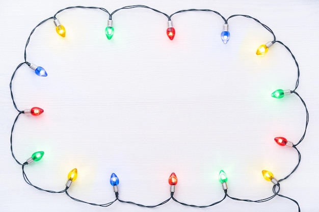 Christmas theme multicolored illuminated garland in retro style on a white wooden background with