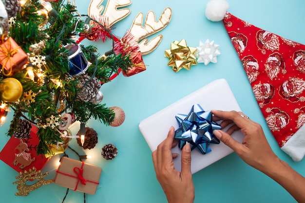 Christmas theme with woman wrapping gift box. Flat lay, top view