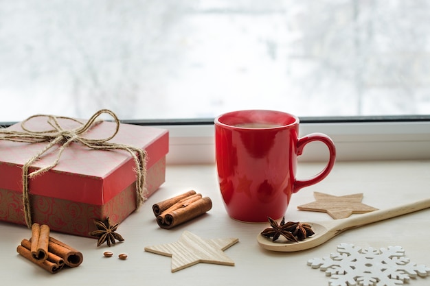 Composizione nel periodo natalizio con tazza rossa e regalo sul davanzale