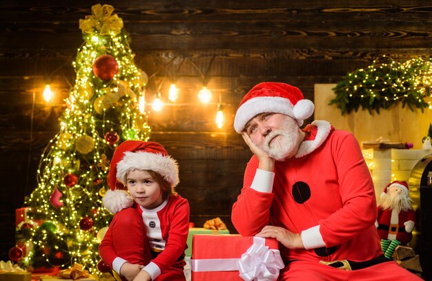 クリスマスの時期の幸せな休日クリスマスはサンタクロースの男と小さなサンタの男の子をクリスマスにプレゼントします