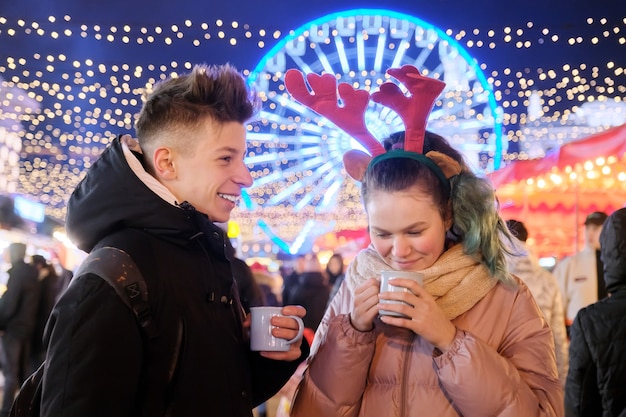 Tempo di natale, vacanze di capodanno. giovani, coppia di adolescenti che si divertono al mercatino di natale