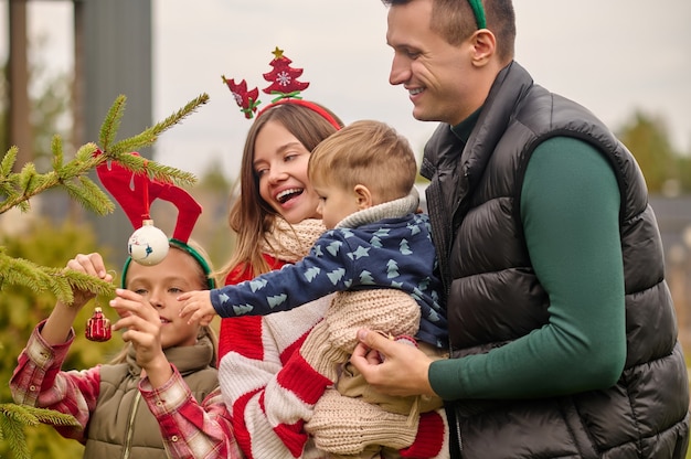 Foto periodo natalizio. persone sorridenti che decorano un albero di natale