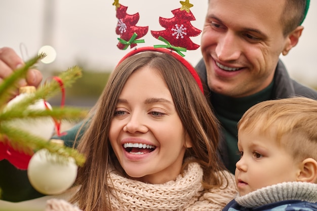 Foto periodo natalizio. persone sorridenti che decorano un albero di natale