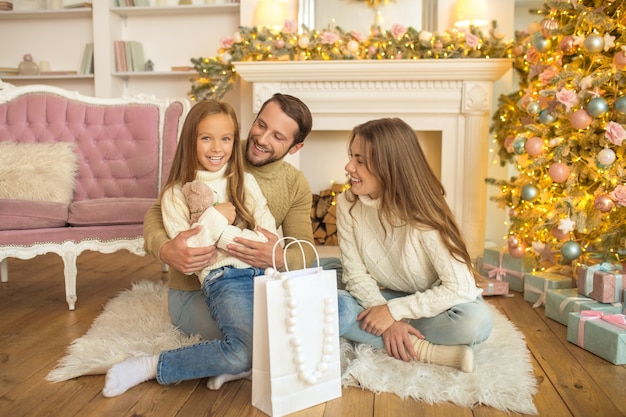 Periodo natalizio. giovani genitori che danno il regalo di natale alla loro figlia