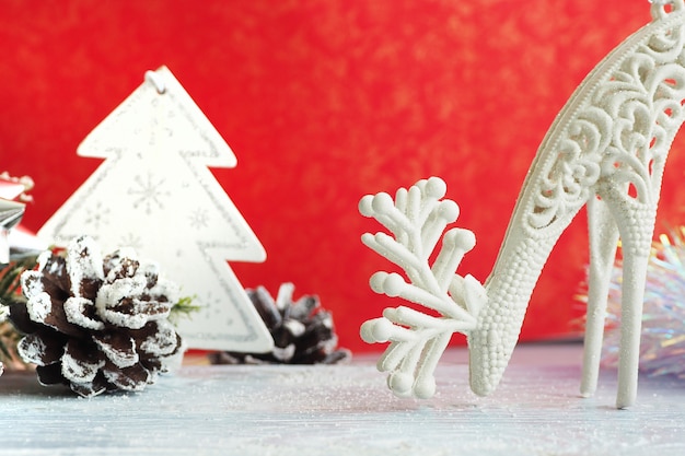 Christmas toy deer and Christmas tree, cones, tinsel and artificial snow on a gray wooden background. Space for text.

