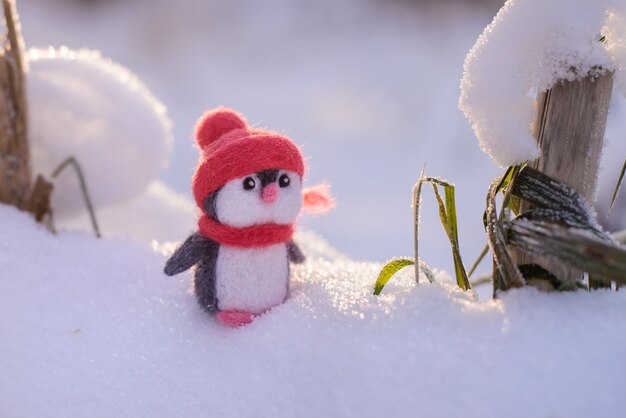 Christmas toy felted wool cute little penguin in a winter red hat and scarf on a sunny winter day