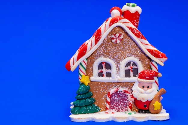 青い背景の上のサンタクロースとクリスマスのおもちゃの家