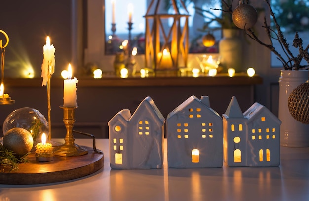 Christmas toy houses with burning candles on  table