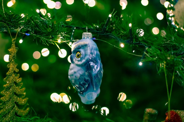 Christmas toy owl on a Christmas tree with blurred sides from the lights Celebrating the New Year and Christmas