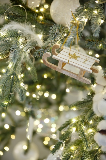 Christmas toy sled hanging on branch of spruce with garland