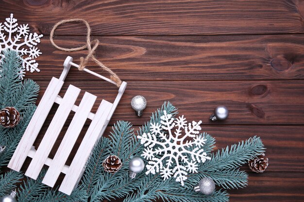 Christmas toy sledge with fir-tree branch on a brown background.