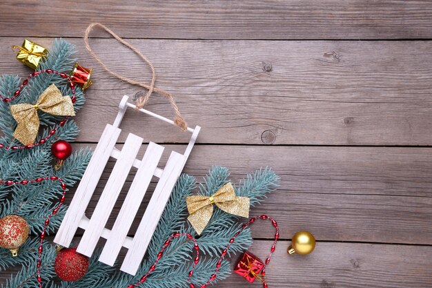 Christmas toy sledge with fir-tree branch on a grey background