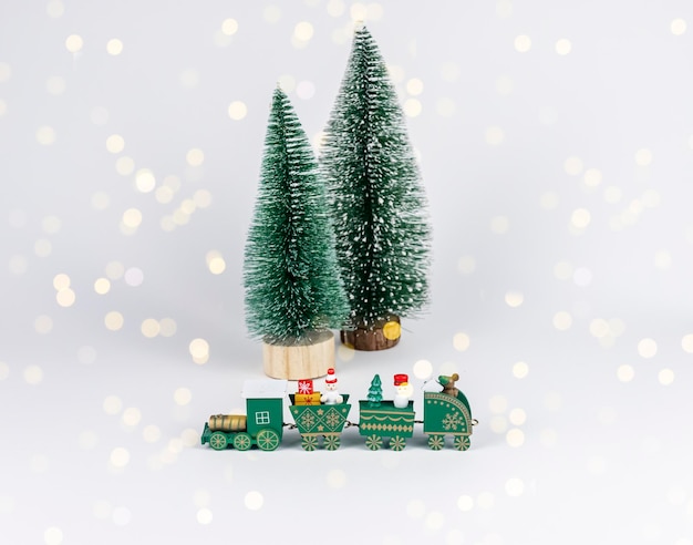 Christmas toy train and tiny fir trees among garland lights composition for postcard