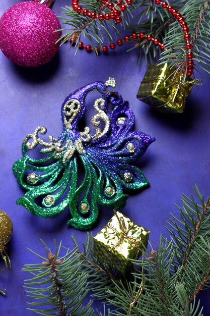 Christmas toys colored toy fire bird candy cane Christmas tree branches on a purple background Christmas concept Closeup