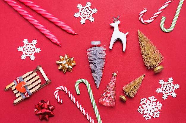 Christmas toys figurines lollipops and candles on a red background Top view