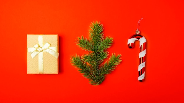 Christmas toys gift box and spruce branch on red background Top view