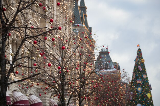 クリスマスのおもちゃが枝からぶら下がっていて、モスクワの建物の正面に花輪が輝いています