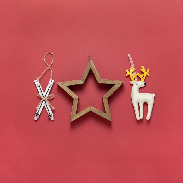 Рождественские игрушки деревянные лыжи, белый войлочный игрушечный олень и деревянная полая звезда на темно-красном