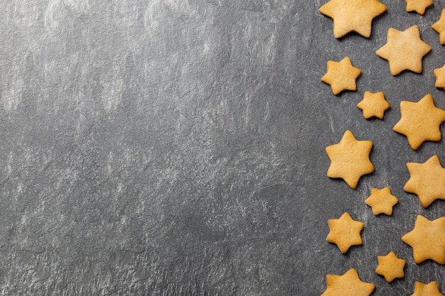 Christmas traditional gingerbread stars cookies on a dark stone background Top view Copy space