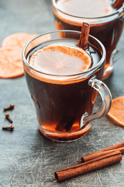 Christmas traditional hot beverage mulled wine with spices and orange slices in a glass cups on a table