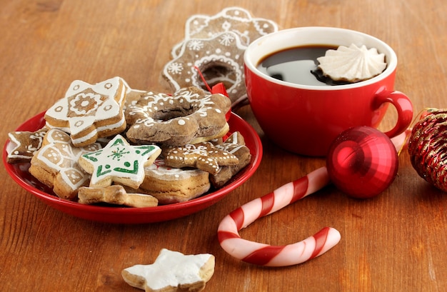 Christmas treats on plate and cup of coffe on wooden table close-up