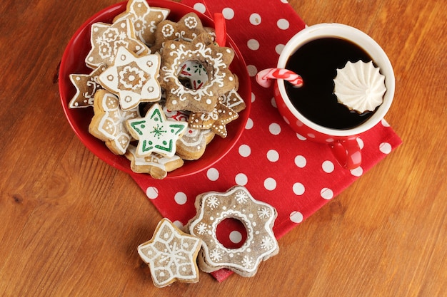 Christmas treats on plate and cup of coffe on wooden table close-up