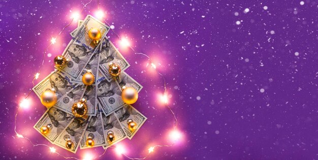 Christmas tree of 100 dollar bills on purple background with copyspace and snow, fairy lights. Decor of finance, savings, wealth, expenses in new year. Flatly. Stack of $ 100, Investments, business