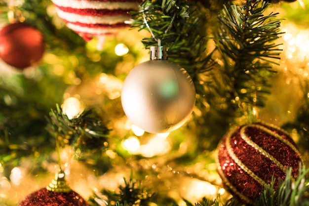 Christmas tree assembled with ornaments. Red, silver and gold balls, gift boxes, lights, Santa Claus and others. Selective focus.