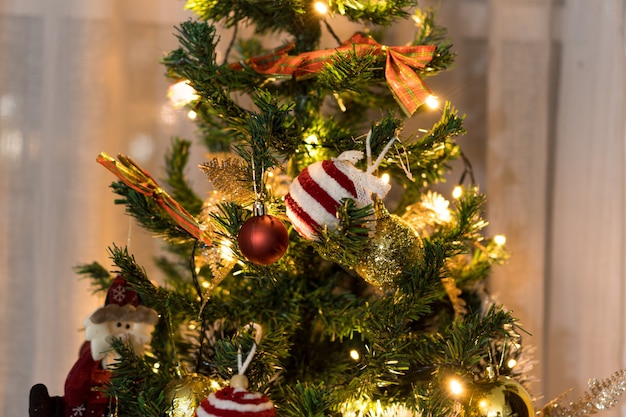 Christmas tree assembled with ornaments. Red, silver and gold balls, gift boxes, lights, Santa Claus and others. Selective focus.