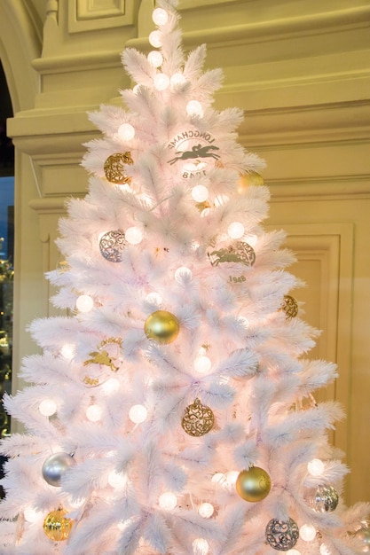 Christmas tree background and Christmas decor Gold shiny balls and garland on white fir tree