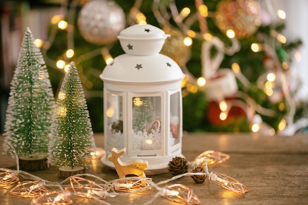ランタン、松の葉、松ぼっくり、安物の宝石の木製のトナカイとクリスマスツリーの背景色。