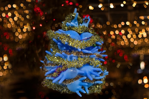 保護マスクの花輪を背景に青い医療用手袋のクリスマスツリー