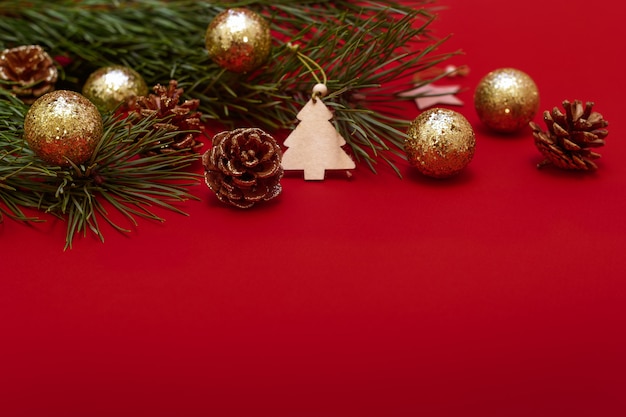 Christmas tree branch decorated with shining balls pine cones and wooden toys on a red background