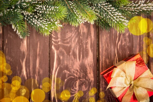 Christmas tree branch and gift box on wood background. Xmas holiday concept