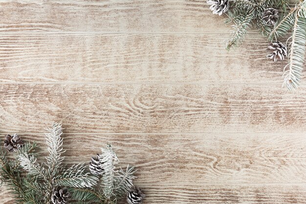 Photo christmas tree branch with pine cones on rustic wooden table. winter background with copy space. top view. flat lay