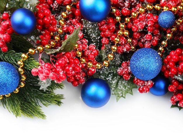 Christmas tree branch with red berries and decorations on white background