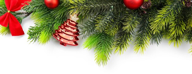 Christmas tree branch with red berries and decorations on white surface