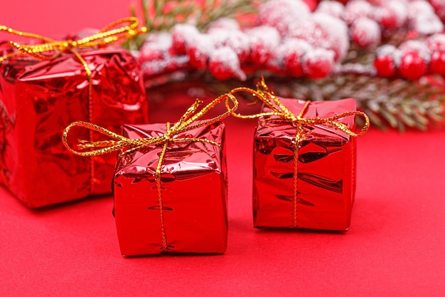 Christmas tree branch with toys and a gift on a red background closeup