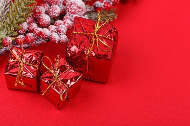 Christmas tree branch with toys and a gift on a red background closeup