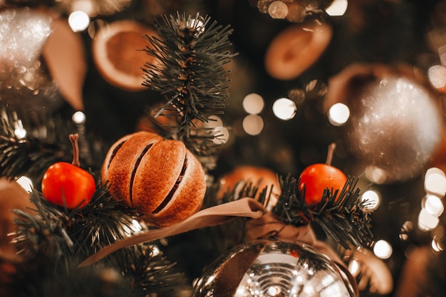 Christmas tree branches decorated with dried oranges cherry Cozy details and golden bokeh garlands