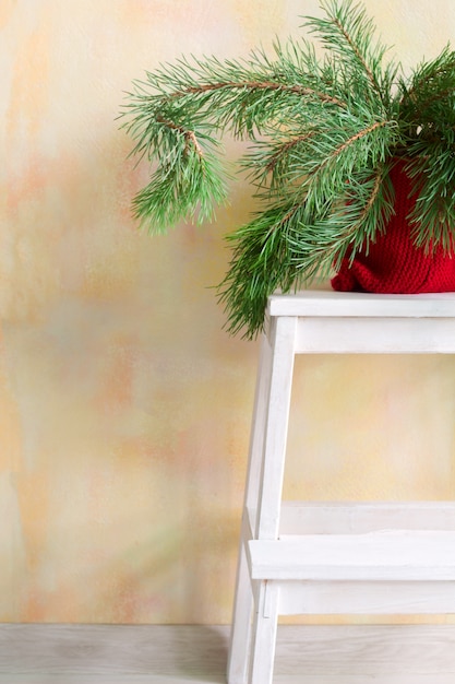 Christmas tree branches in a pot on a chair, home holidays decor