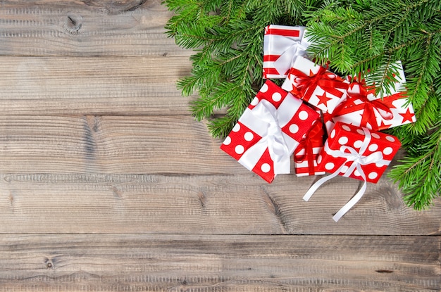 Christmas tree branches and red gifts decoration on wooden background