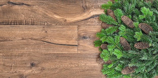 Christmas tree branches over rustic wooden background. green border from undecorated evergreen twigs