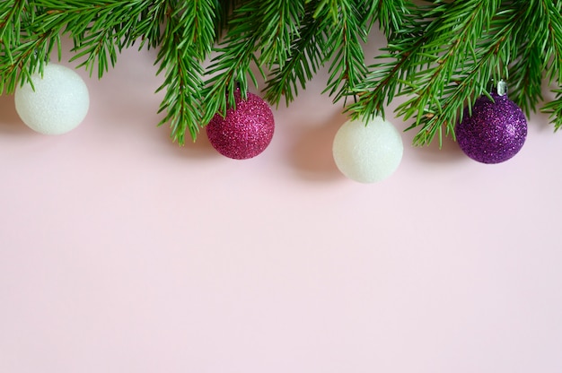 Rami di albero di natale con decorazioni natalizie giocattoli palle, cornice su uno sfondo rosa. spazio per il testo