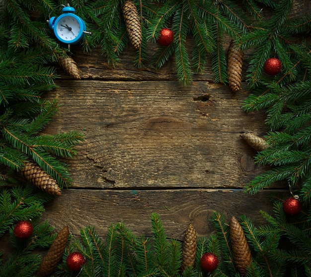 Christmas tree branches with cones and christmas decorations on wooden texture ready for your design