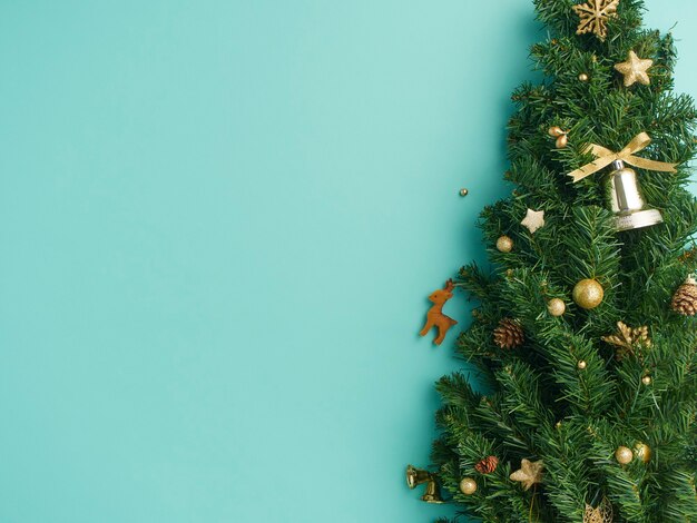 Christmas tree branches with gold baubles, stars, pine cones on light blue background