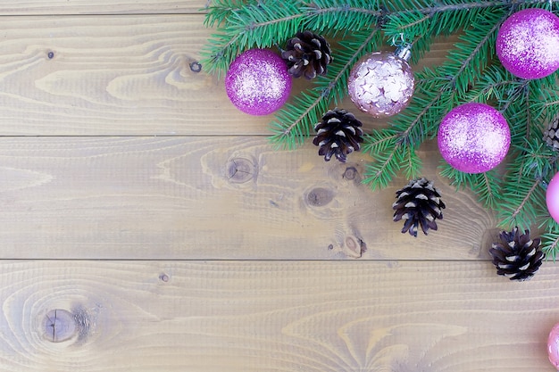 Christmas tree branches with red decorations on a wooden wall background. Template for greeting card or design. Virtical banner with copy space.